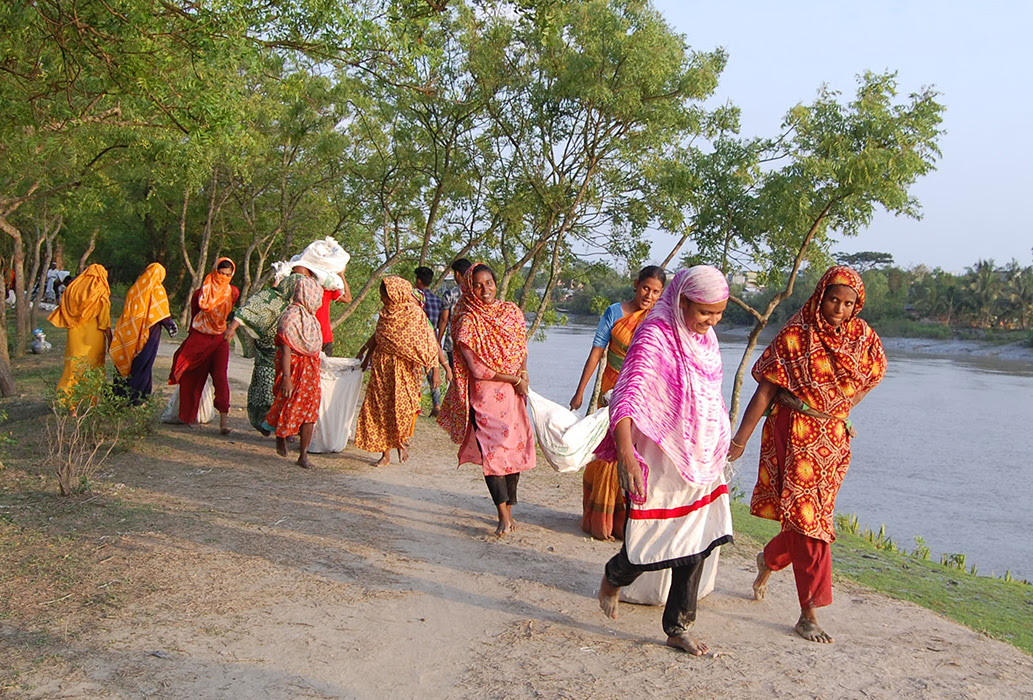 South Asian women walking beside a lake carrying bags