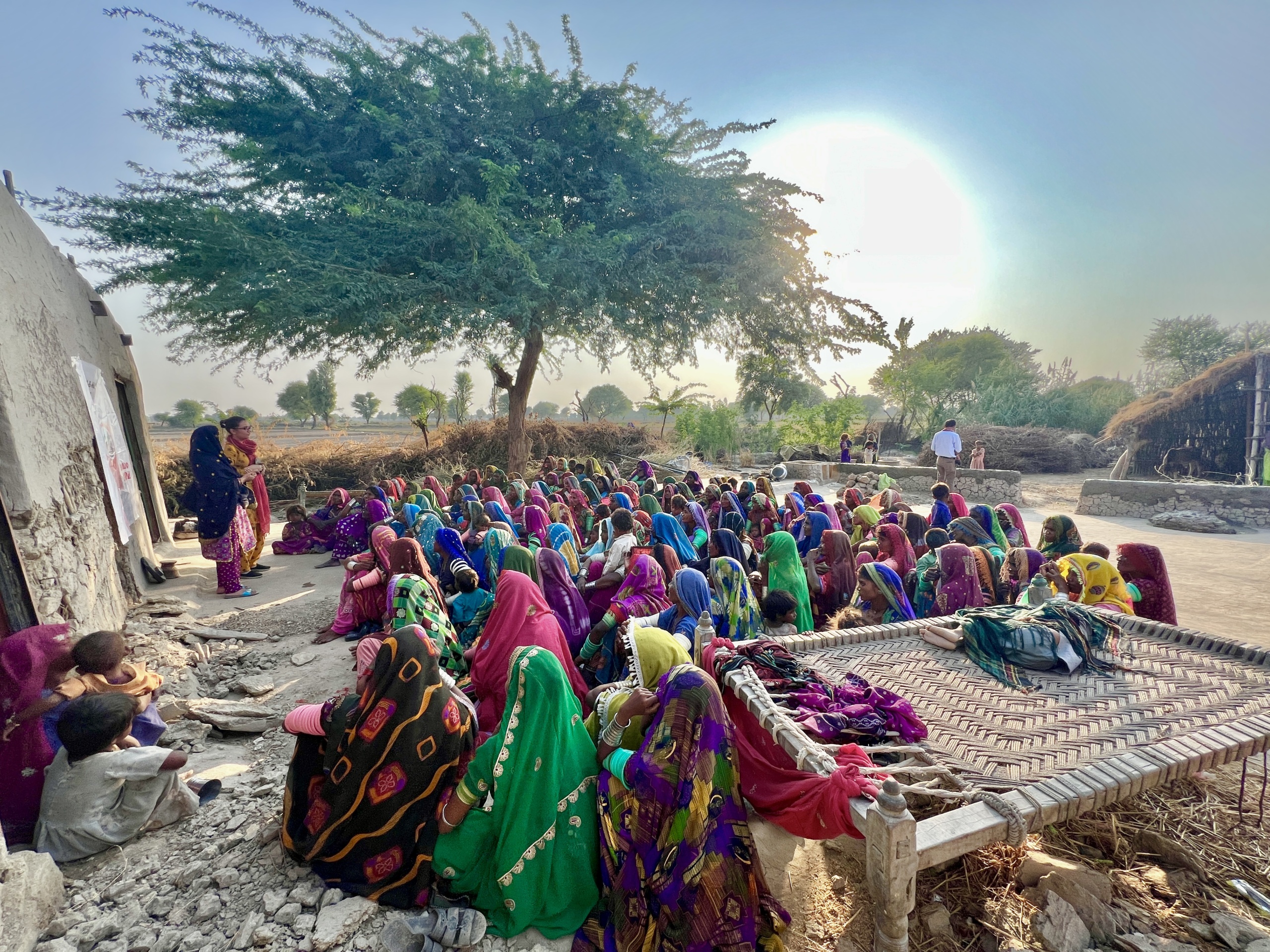 Many women sitting outside listening to two women speakers.