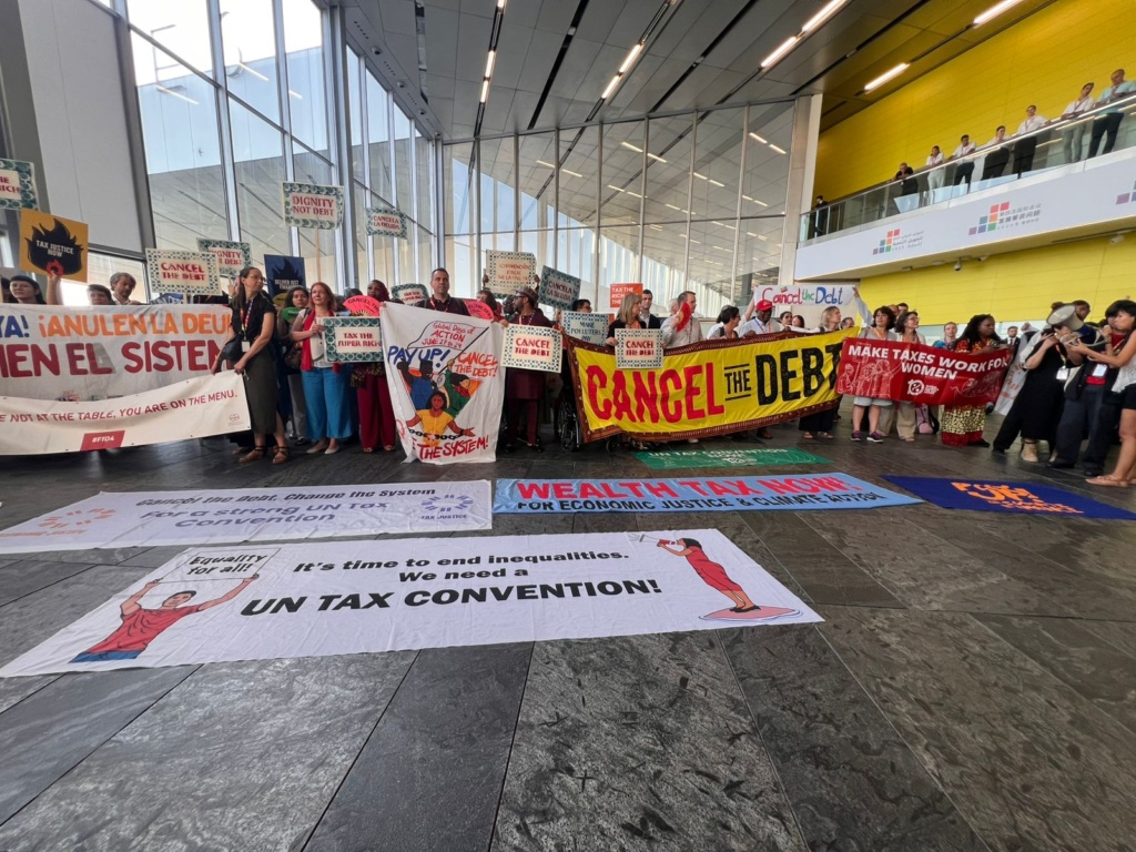 People gathered inside with banners with statements like "Cancel the Debt" and "It's time to end inequalities."